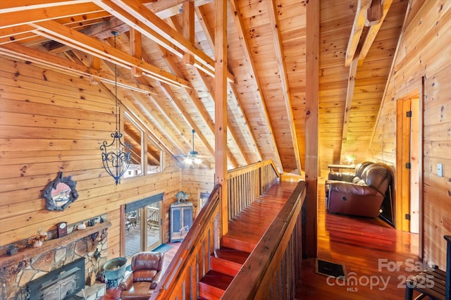 staircase featuring lofted ceiling with beams, ceiling fan, wood walls, and wood ceiling