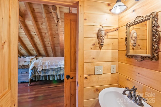 bathroom featuring beam ceiling, sink, wood-type flooring, wooden walls, and wood ceiling