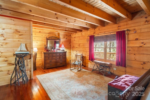 sitting room featuring beam ceiling, hardwood / wood-style flooring, and wood walls