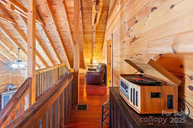 hall featuring wooden walls, dark wood-type flooring, beamed ceiling, and wooden ceiling