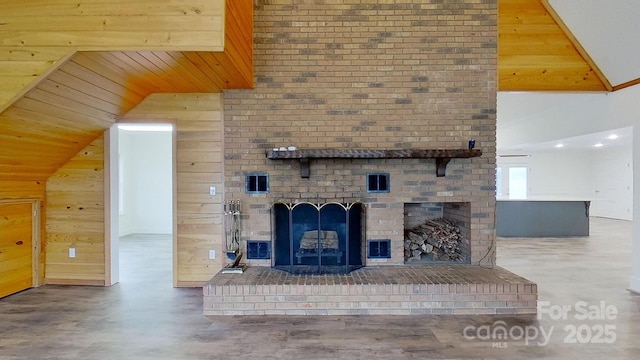 unfurnished living room with wood walls, vaulted ceiling, and a brick fireplace