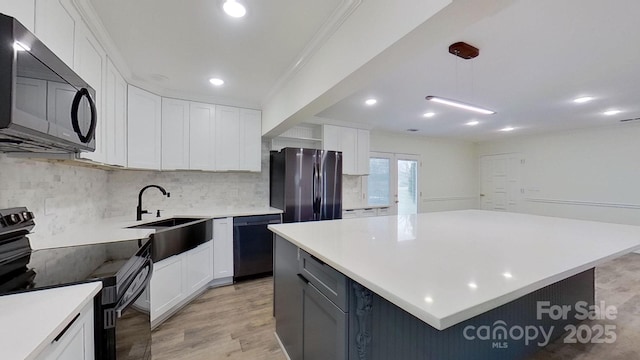 kitchen featuring a kitchen island, pendant lighting, white cabinets, black appliances, and light wood-type flooring