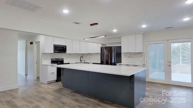 kitchen featuring black electric range oven, french doors, white cabinets, fridge, and a kitchen island