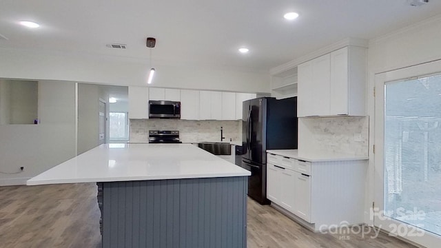 kitchen with white cabinets, stainless steel appliances, decorative light fixtures, and a kitchen island