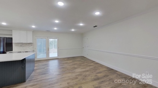 kitchen featuring white cabinetry, french doors, black fridge, backsplash, and ornamental molding