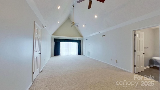 carpeted empty room with ceiling fan and high vaulted ceiling