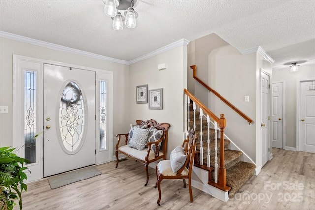 entrance foyer featuring light wood-type flooring, a textured ceiling, and ornamental molding