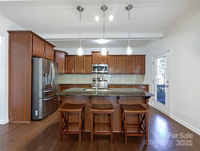 kitchen with a center island with sink, stainless steel appliances, decorative light fixtures, and sink