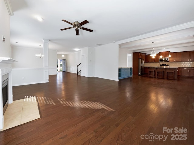 unfurnished living room with ceiling fan with notable chandelier, dark hardwood / wood-style flooring, crown molding, and a tile fireplace