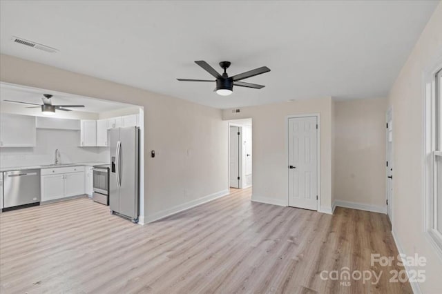 kitchen featuring sink, ceiling fan, light wood-type flooring, appliances with stainless steel finishes, and white cabinetry