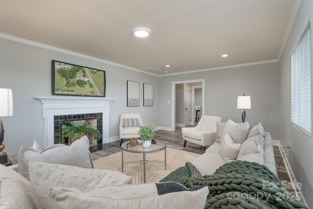 living room featuring a tile fireplace, light hardwood / wood-style flooring, plenty of natural light, and ornamental molding