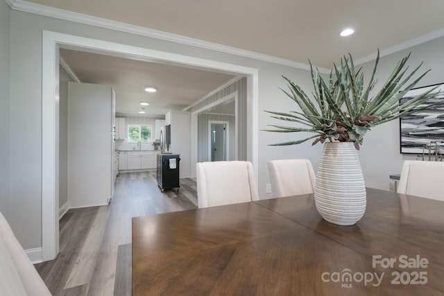 unfurnished dining area featuring wood-type flooring, crown molding, and sink