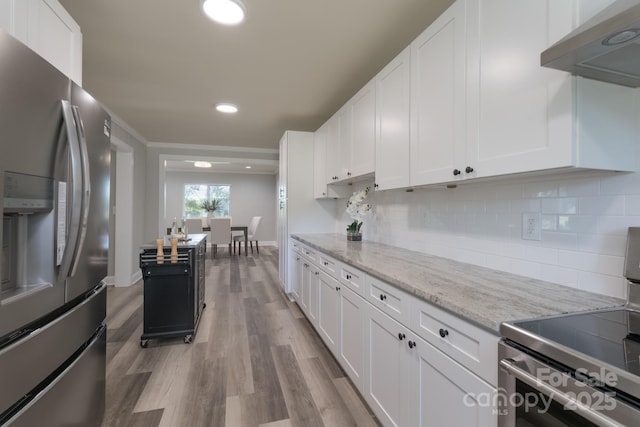 kitchen with light stone countertops, appliances with stainless steel finishes, extractor fan, light hardwood / wood-style flooring, and white cabinets