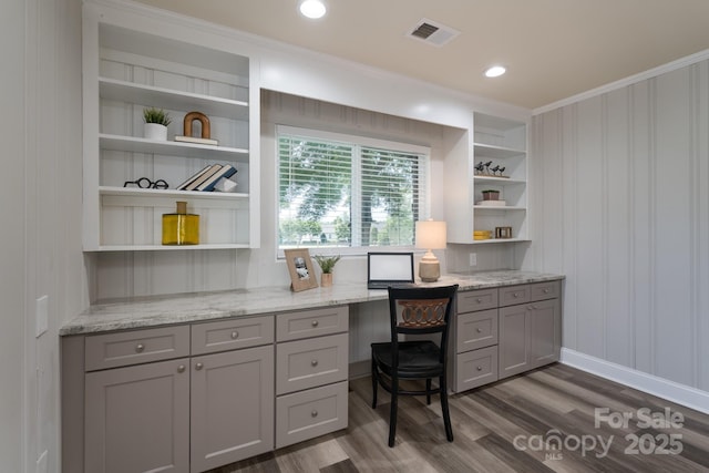 office space with built in features, built in desk, dark wood-type flooring, and ornamental molding