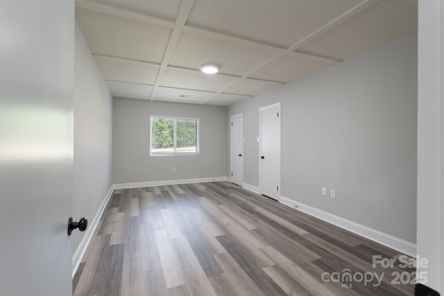 spare room featuring wood-type flooring and coffered ceiling