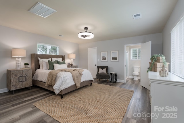 bedroom featuring ensuite bathroom and dark wood-type flooring