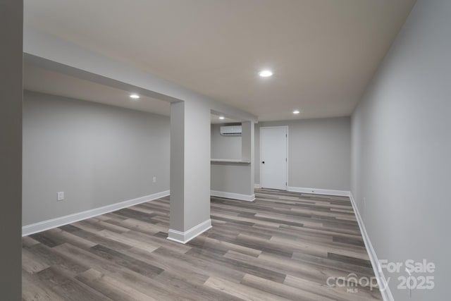 basement featuring a wall mounted AC and hardwood / wood-style floors