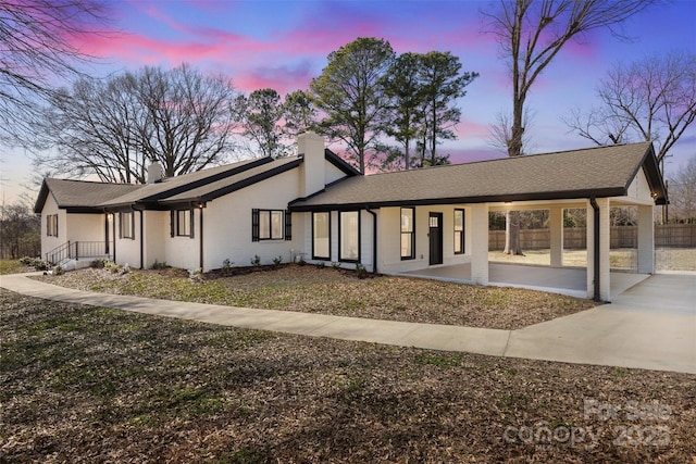 mid-century modern home featuring brick siding, fence, and a chimney