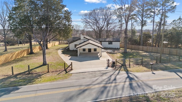 view of front of house with concrete driveway, a fenced front yard, and a front yard