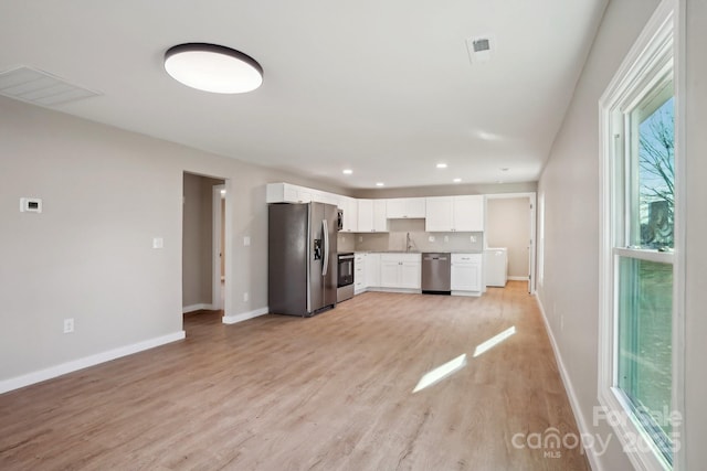 kitchen with white cabinets, plenty of natural light, light wood-type flooring, and stainless steel appliances