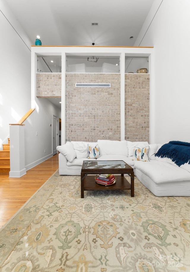 living room with brick wall and wood-type flooring