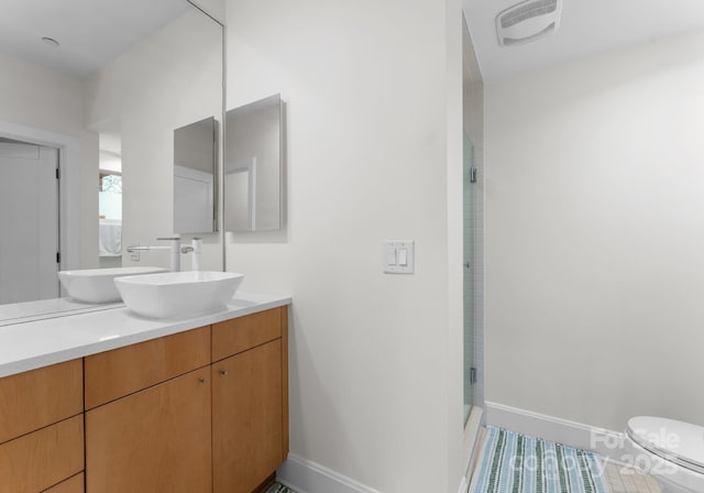 bathroom featuring walk in shower, vanity, and toilet