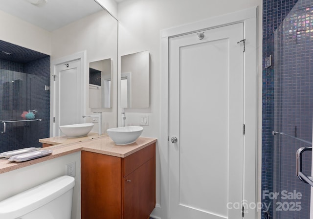 bathroom featuring vanity, a shower with shower door, and toilet