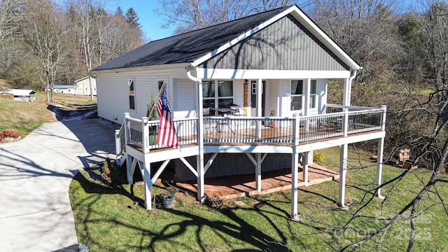 rear view of property with a wooden deck and a lawn