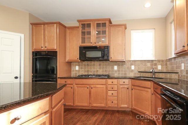 kitchen featuring backsplash, dark stone counters, black appliances, sink, and dark hardwood / wood-style flooring