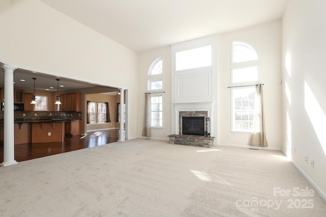 unfurnished living room with a fireplace, a towering ceiling, and dark carpet