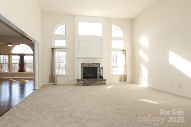 unfurnished living room featuring a towering ceiling, ceiling fan, a fireplace, and carpet floors