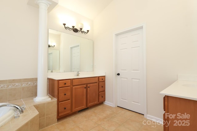 bathroom with tile patterned floors, a relaxing tiled tub, ornate columns, and vanity