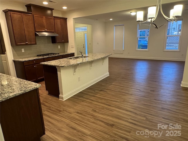 kitchen with sink, dark wood-type flooring, light stone countertops, and stainless steel gas stovetop