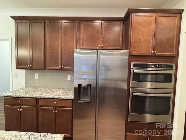 kitchen with stainless steel appliances, backsplash, and light stone counters