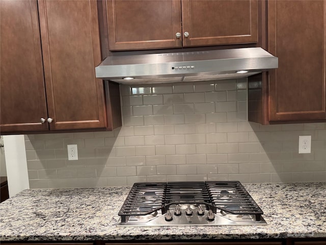 details with light stone counters, stainless steel gas stovetop, and tasteful backsplash