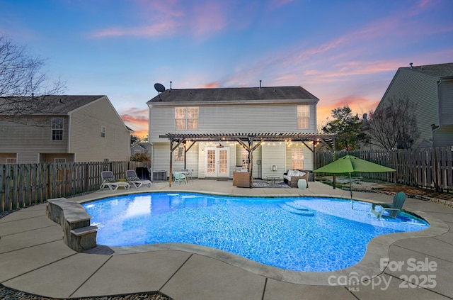 pool at dusk featuring a patio and french doors