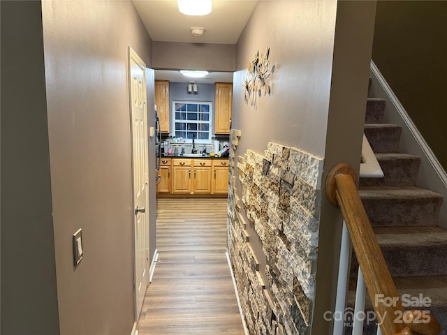 corridor featuring a sink, stairway, and light wood-style flooring