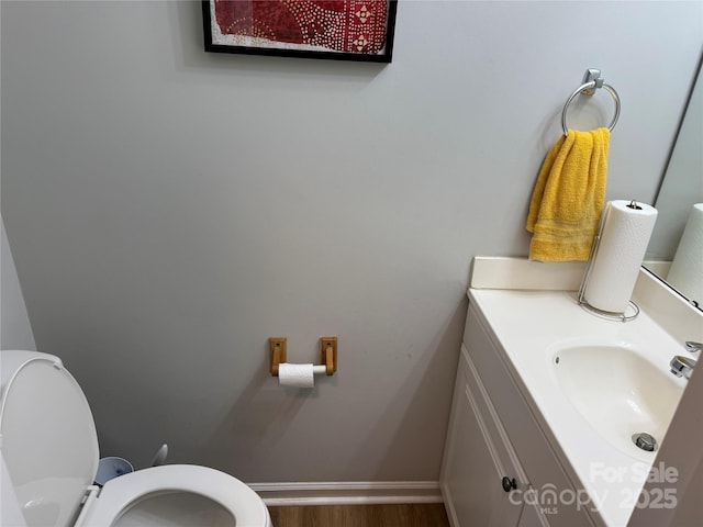 bathroom featuring vanity, toilet, wood finished floors, and baseboards