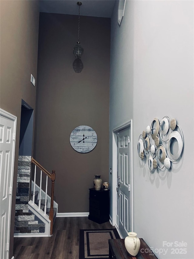 entrance foyer featuring stairway, a high ceiling, baseboards, and wood finished floors