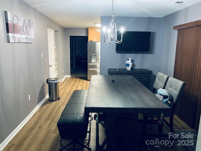 dining room with visible vents, light wood-style flooring, baseboards, and an inviting chandelier