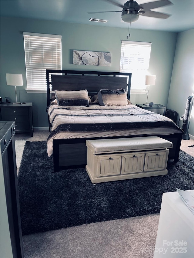 carpeted bedroom with a ceiling fan, visible vents, and baseboards