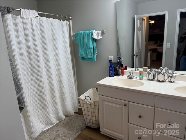 full bath with double vanity, a shower with shower curtain, and a sink