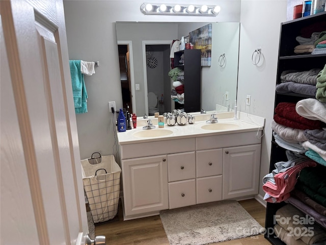 bathroom with a sink, toilet, wood finished floors, and double vanity