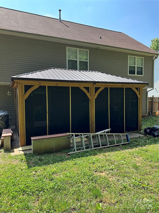 rear view of property with a yard, a sunroom, and metal roof