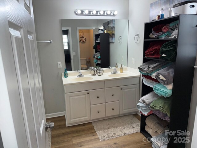 9624 Langston Mill Rd, Charlotte, NC 28216 - full bath with double vanity, a sink, wood finished floors, and toilet