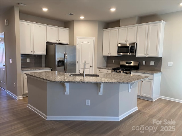 kitchen featuring stainless steel appliances, sink, white cabinets, and a kitchen island with sink