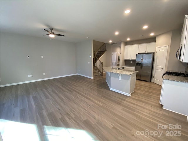 kitchen featuring appliances with stainless steel finishes, white cabinetry, sink, hardwood / wood-style flooring, and a center island with sink