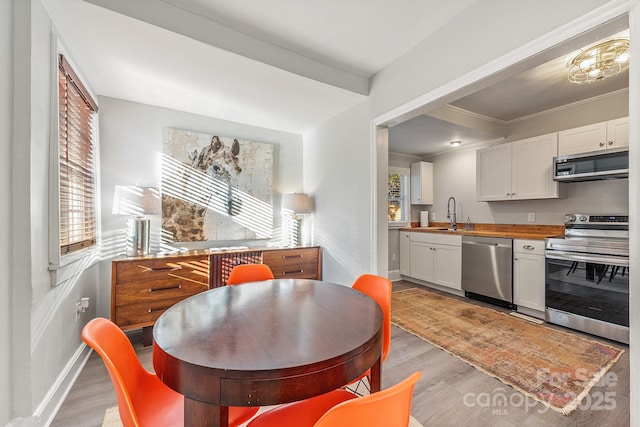 kitchen featuring wood counters, appliances with stainless steel finishes, sink, light hardwood / wood-style flooring, and white cabinetry