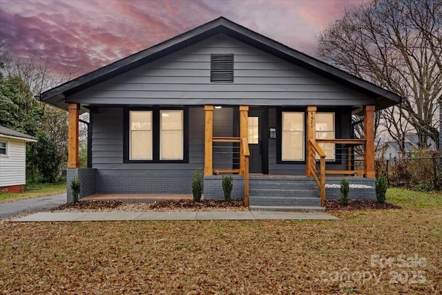 bungalow-style home with a porch and a yard