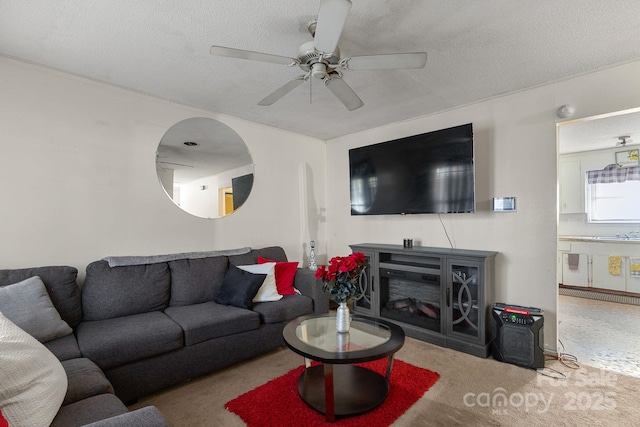 carpeted living room featuring ceiling fan, sink, and a textured ceiling